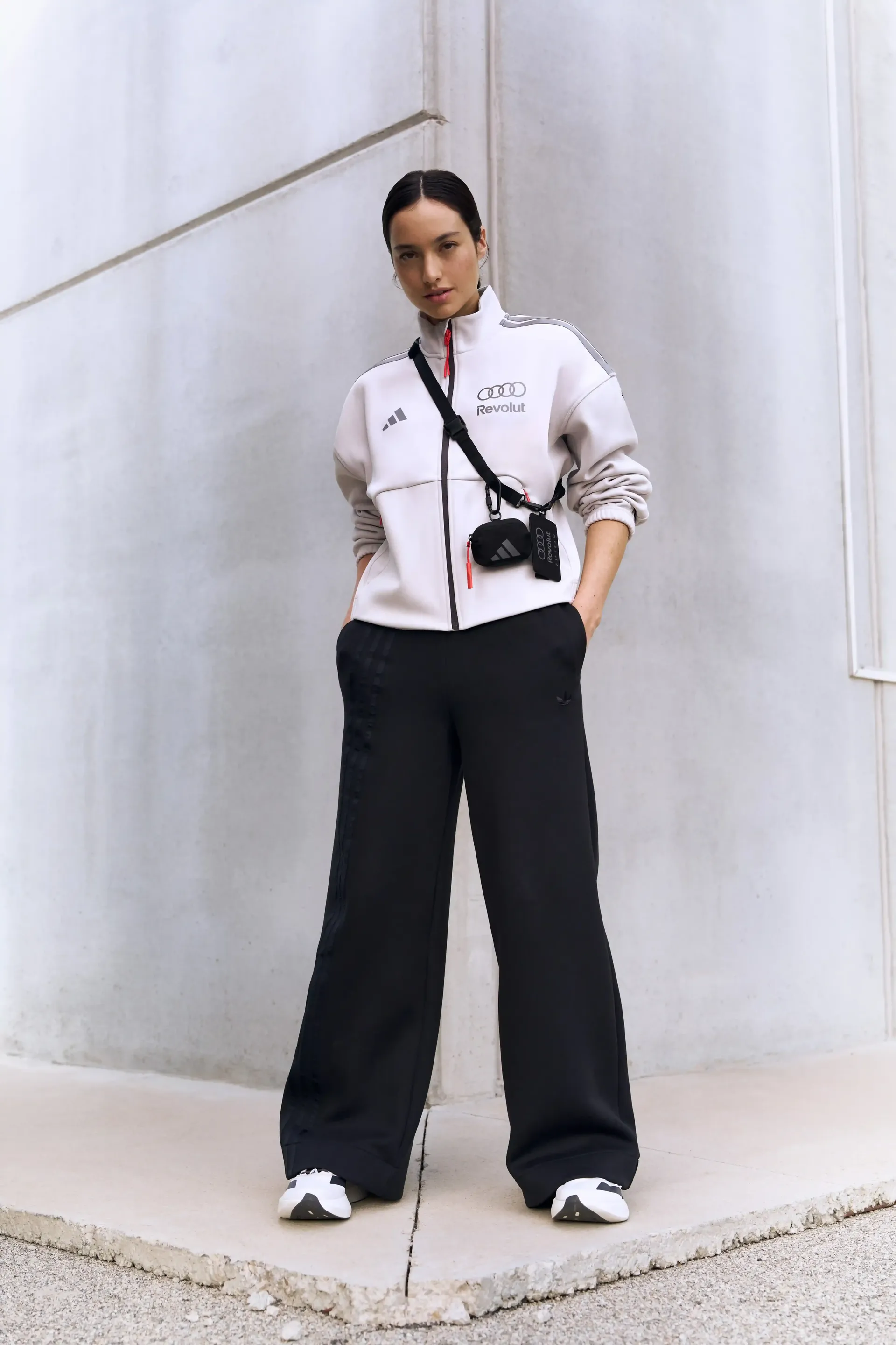 Single portrait of a model light jacket black pants urban wall background minimalist fashion shot