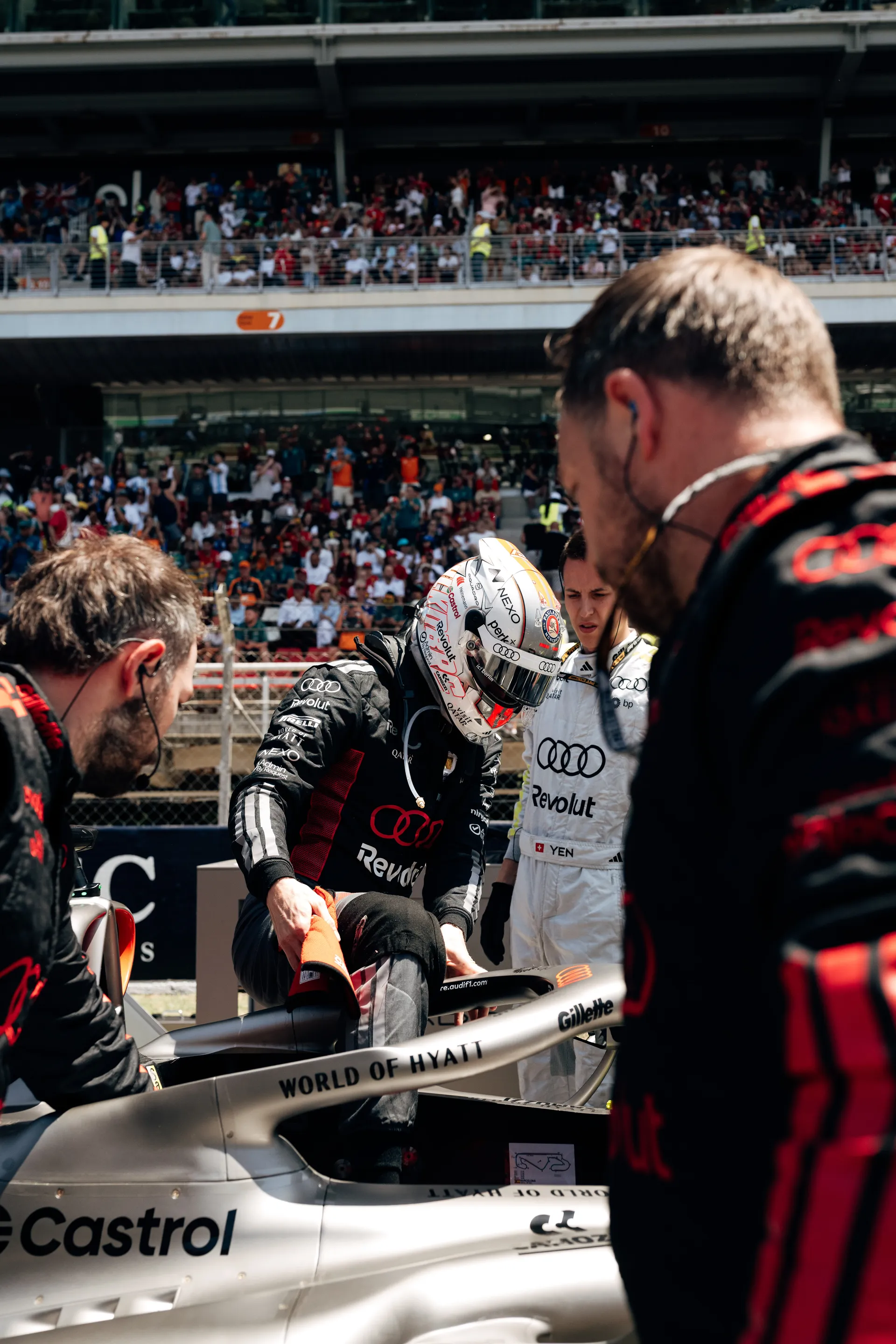Driver seated in the Audi R26 on the grid with Audi Revolut F1® Team engineers preparing the car before the race.