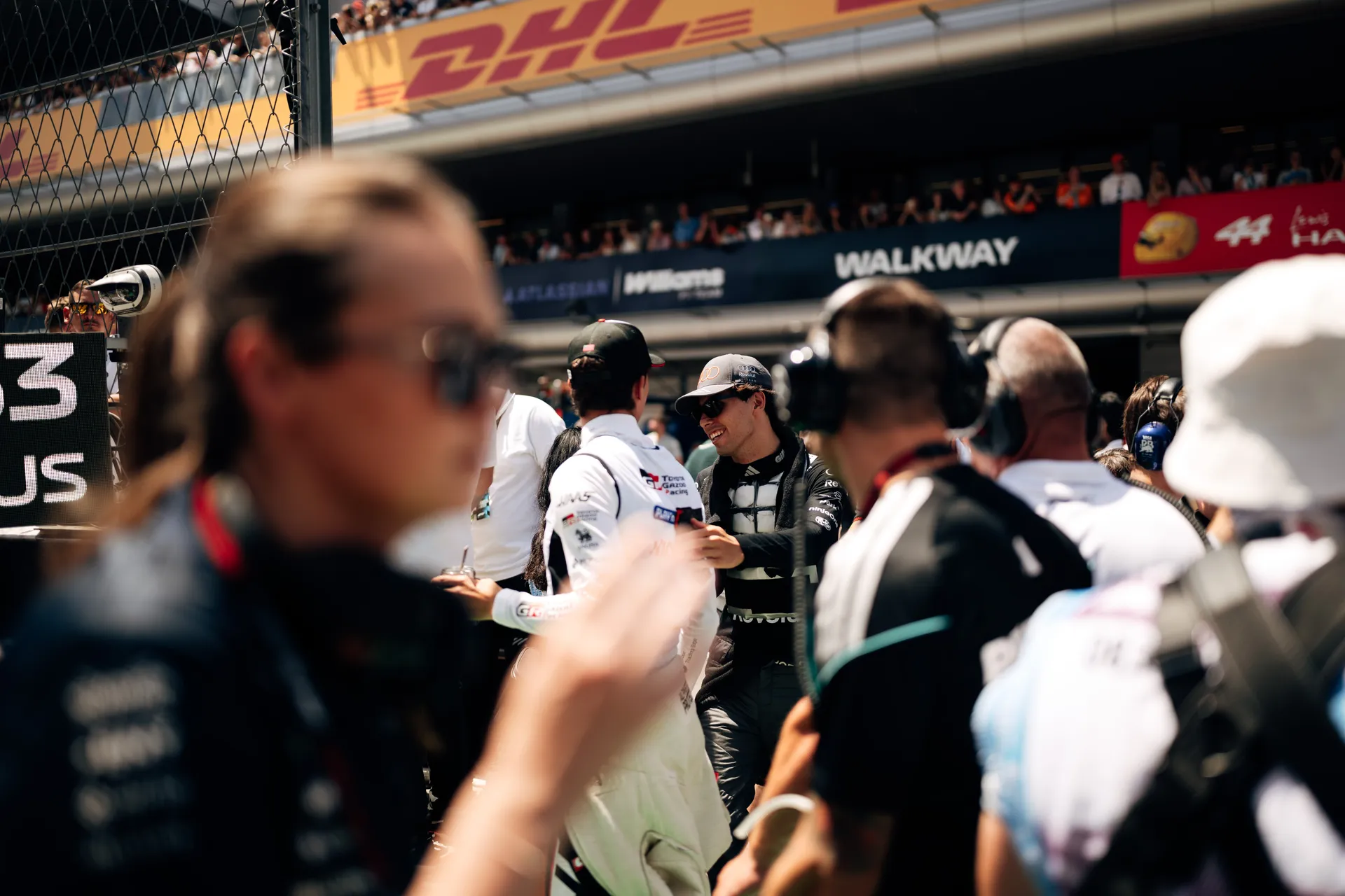 Gabriel Bortoleto greeting another driver on the grid in a pre-race interaction at Circuit de Barcelona-Catalunya.