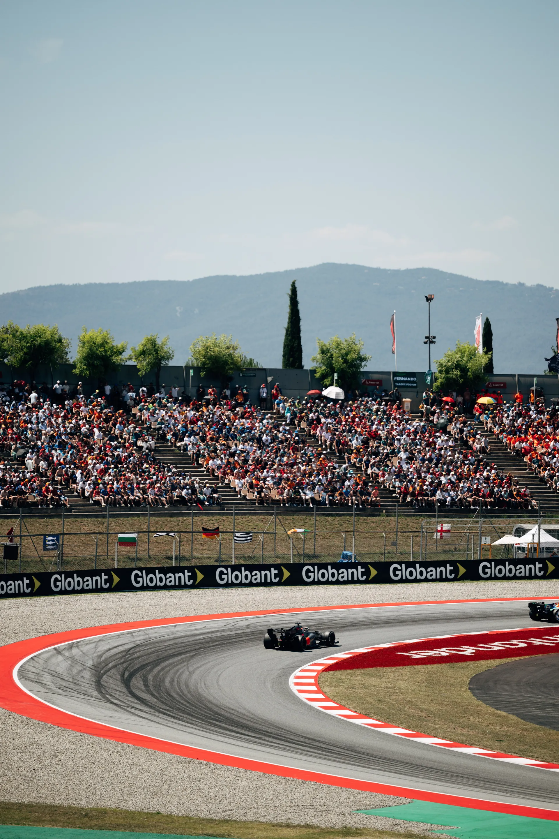 Two Audi R26 cars navigating a corner at Circuit de Barcelona-Catalunya with a full crowd in the background during the race weekend.
