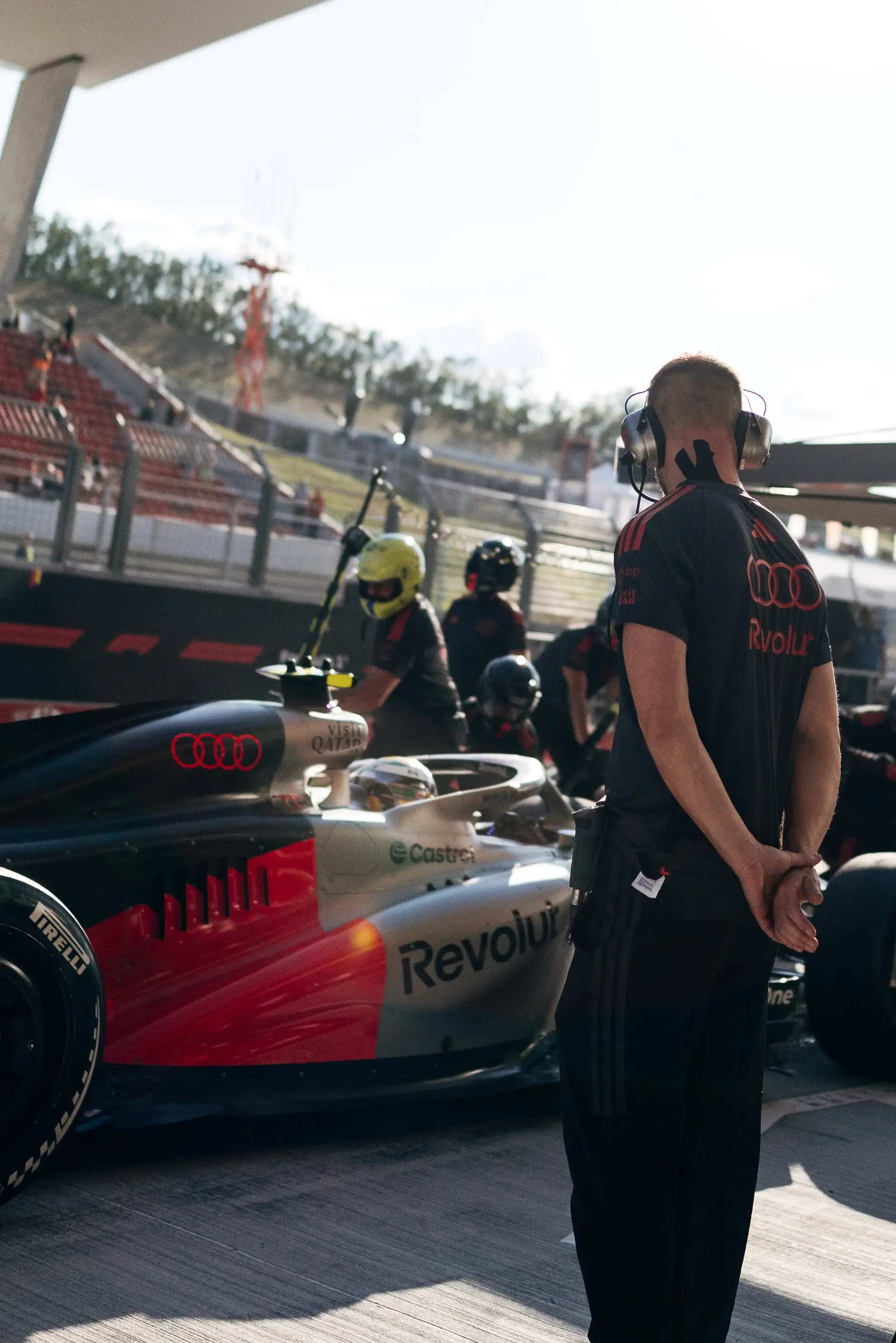 An Audi Revolut F1® Team mechanic stands beside the Audi Revolut F1® Team car Audi R26 in the pit lane before FP2.