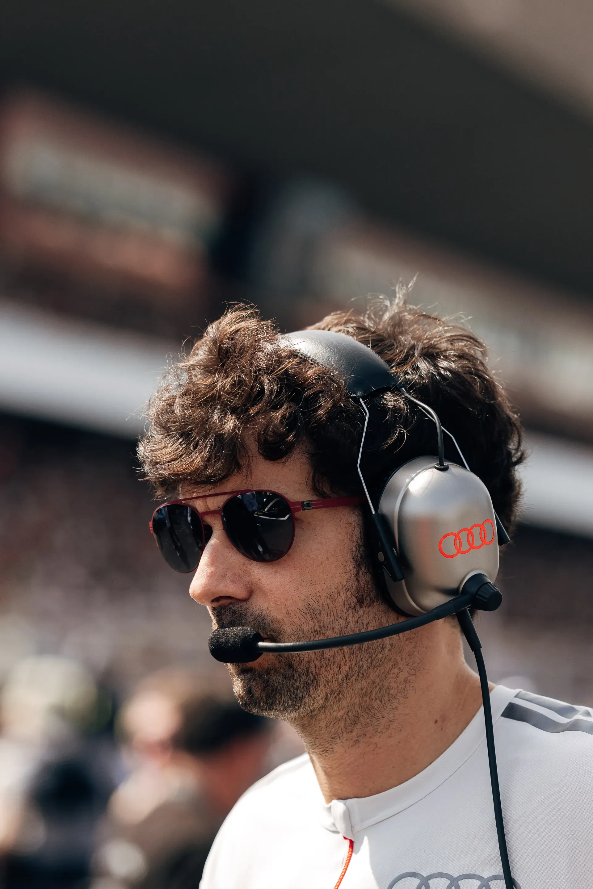 An Audi Revolut F1® Team engineer wearing a headset watches activity from the Hungaroring grid before the race.