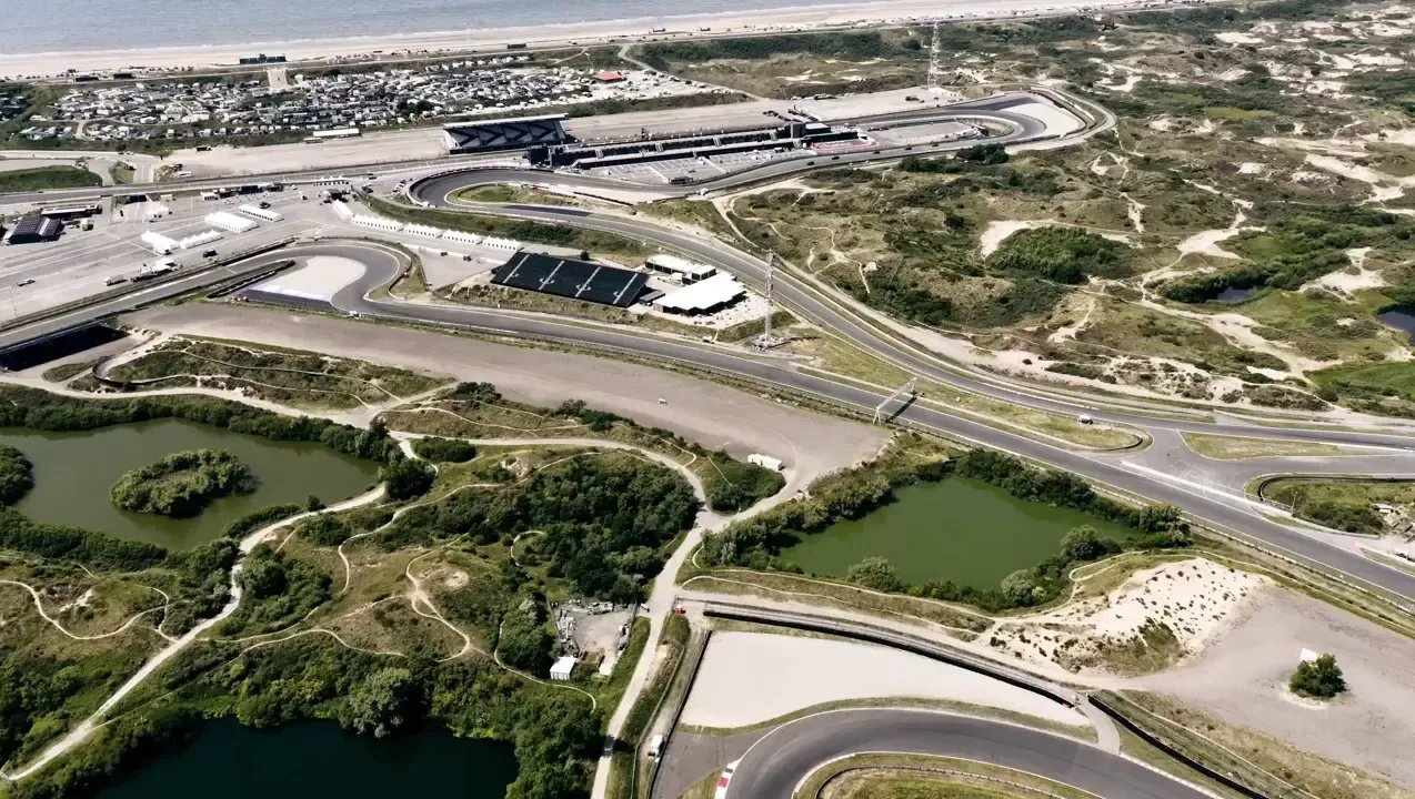 Aerial drone view of Circuit Zandvoort, showing the full Dutch Grand Prix circuit winding through the coastal dunes near the North Sea.