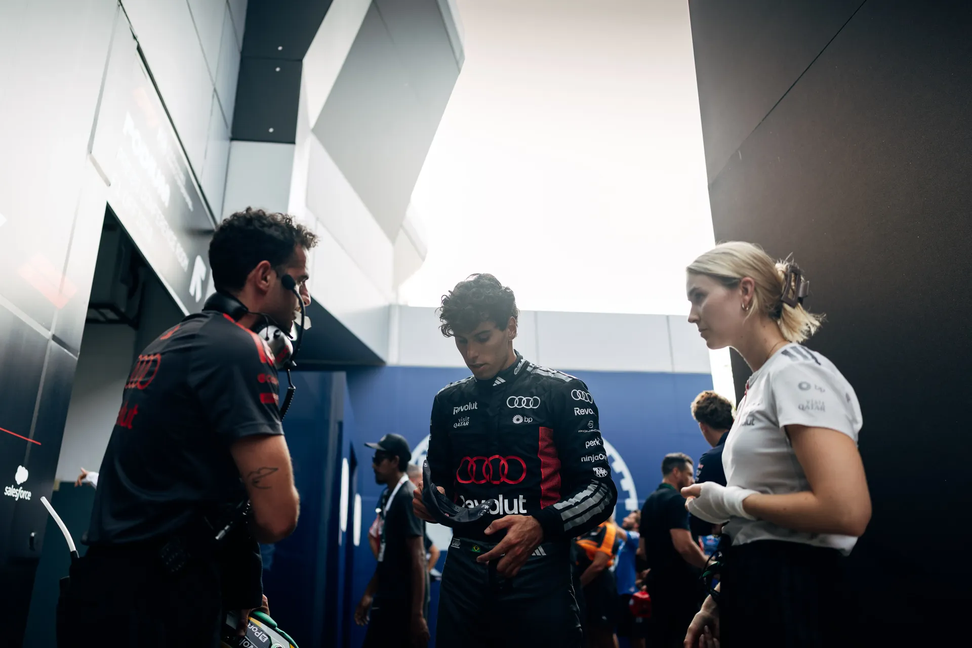 Audi Revolut F1® Team team driver Gabriel Bortoleto standing with crew inside the paddock