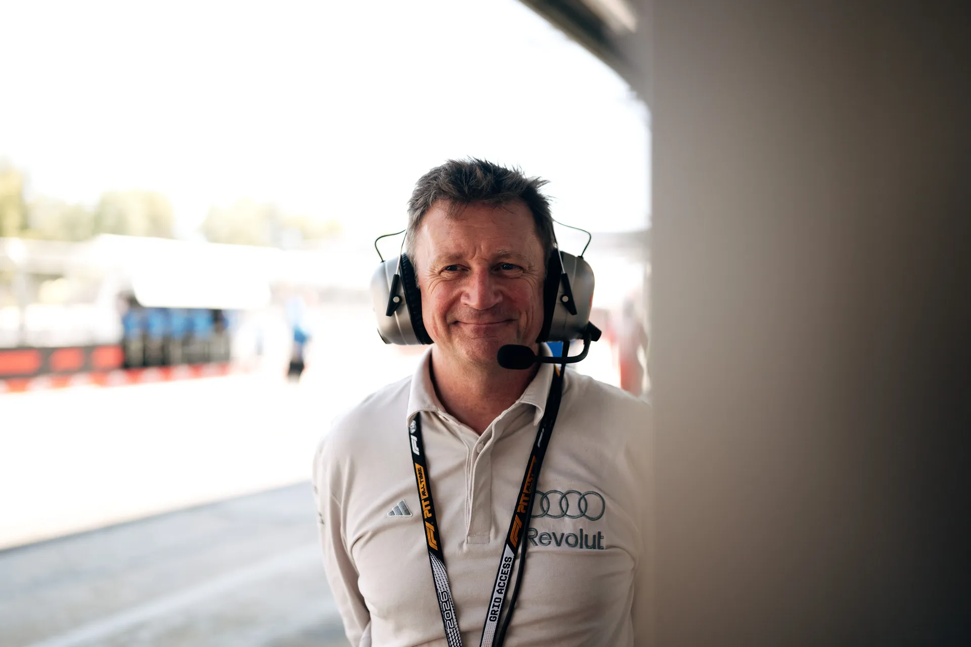 Audi Revolut F1® Team Allan McNish portrait with headset and credentials, standing trackside during FP1 in Barcelona.