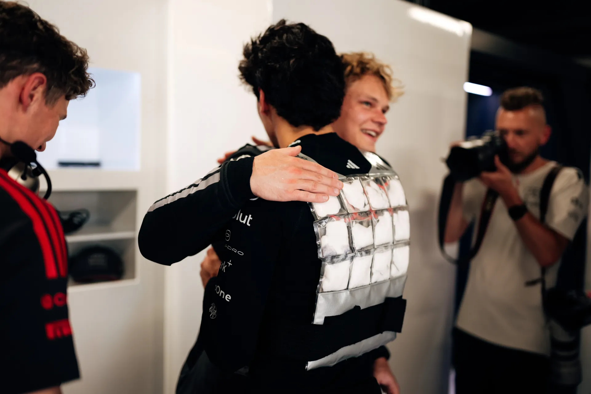 Paul Aron hugging Gabriel Bortoleto, both in Audi Revolut F1® Team race gear, sharing a friendly moment.