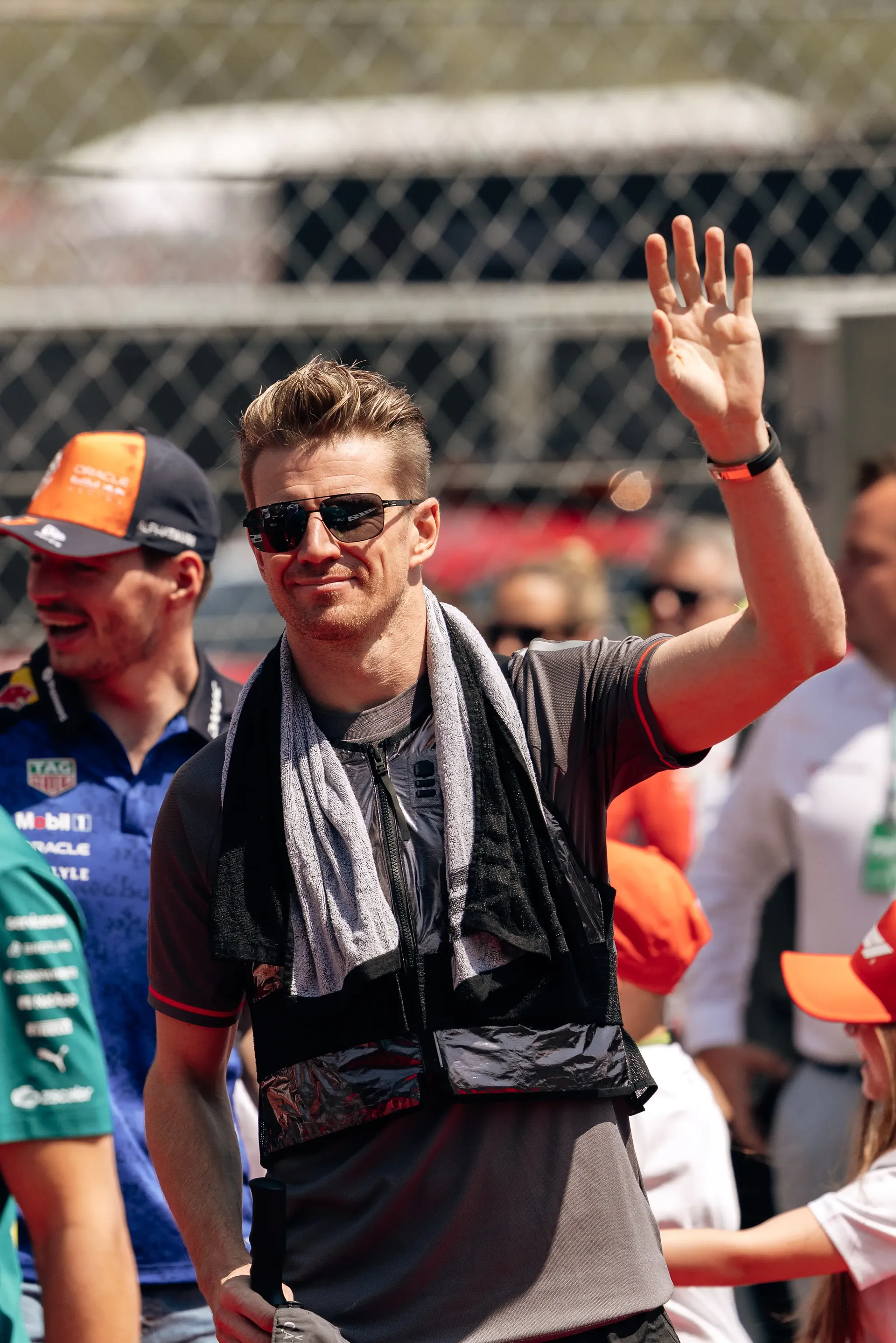 Nico Hulkenberg waves to fans during the drivers' parade at the Hungarian Grand Prix, wearing an Audi Revolut F1® Team shirt with a towel draped around his shoulders as spectators line the circuit.