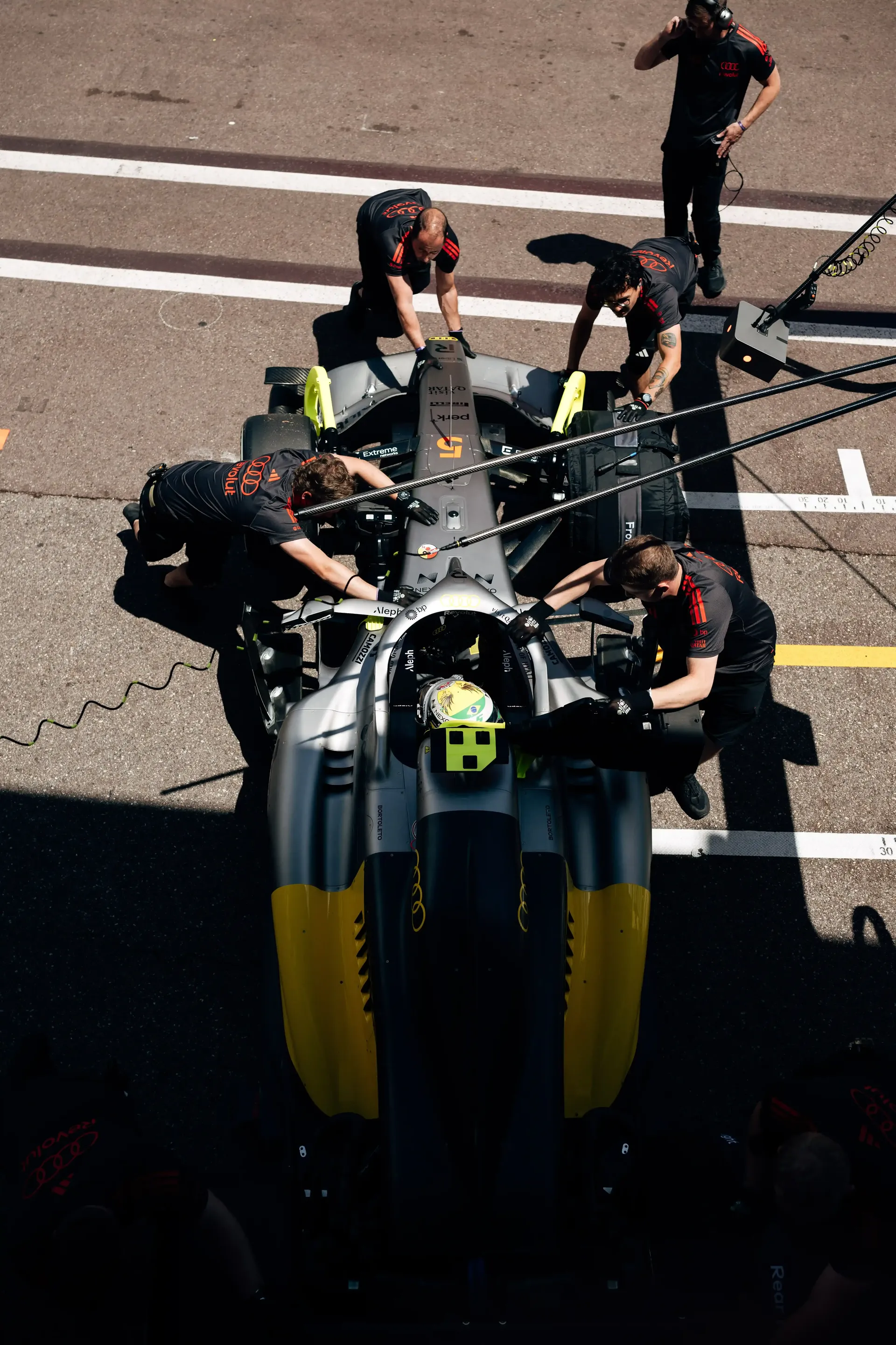 Overhead view of the Audi Revolut F1® Team pit crew surrounding the F1® car during a practice pit stop.