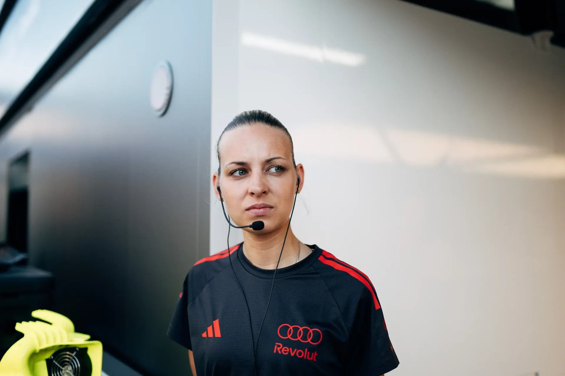 Portrait of an female Audi Revolut F1® Team crew member standing outside the garage area.
