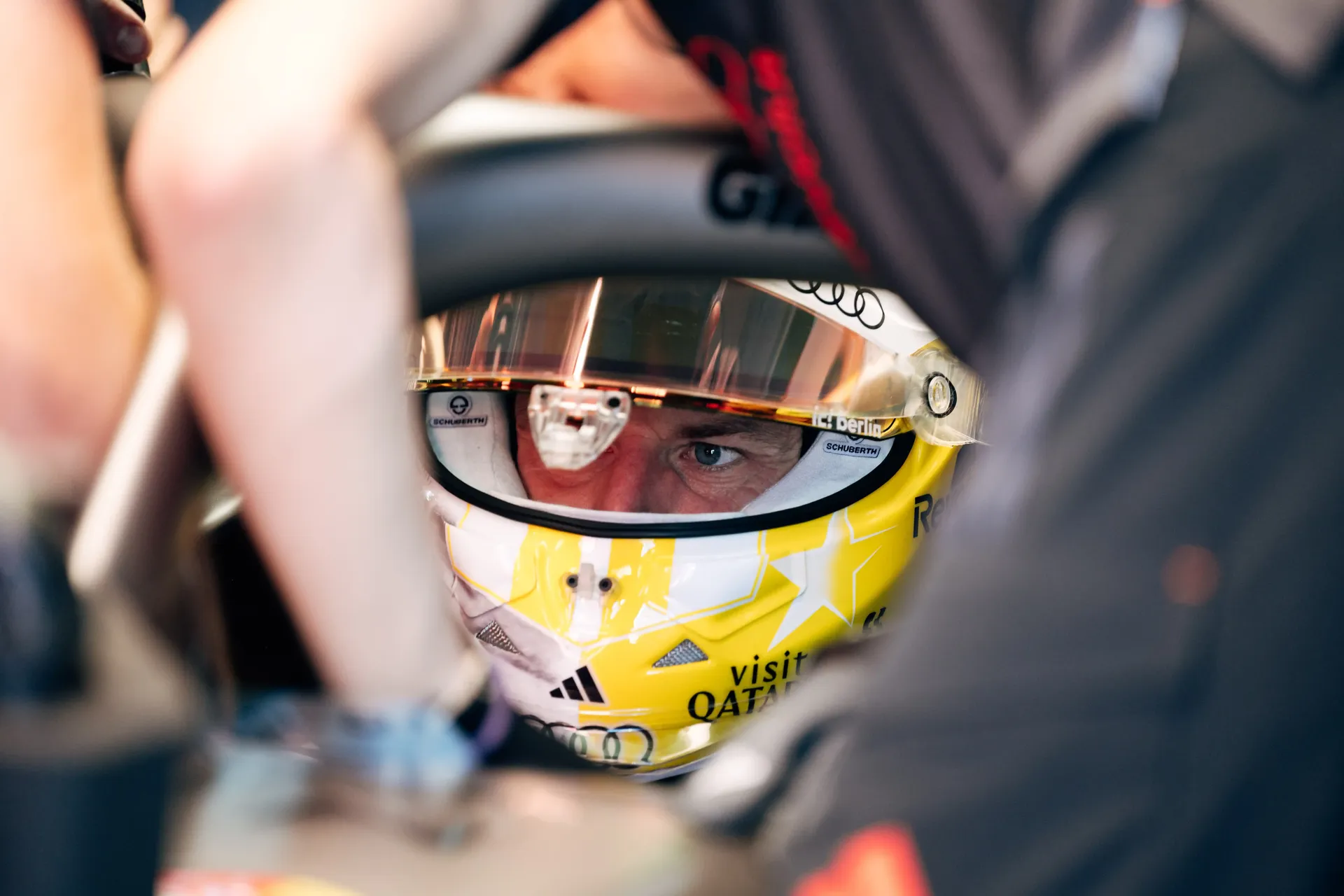 Close-up of a Nico Hulkenberg Audi Revolut F1® Team driver viewed between crew members working around the cockpit.