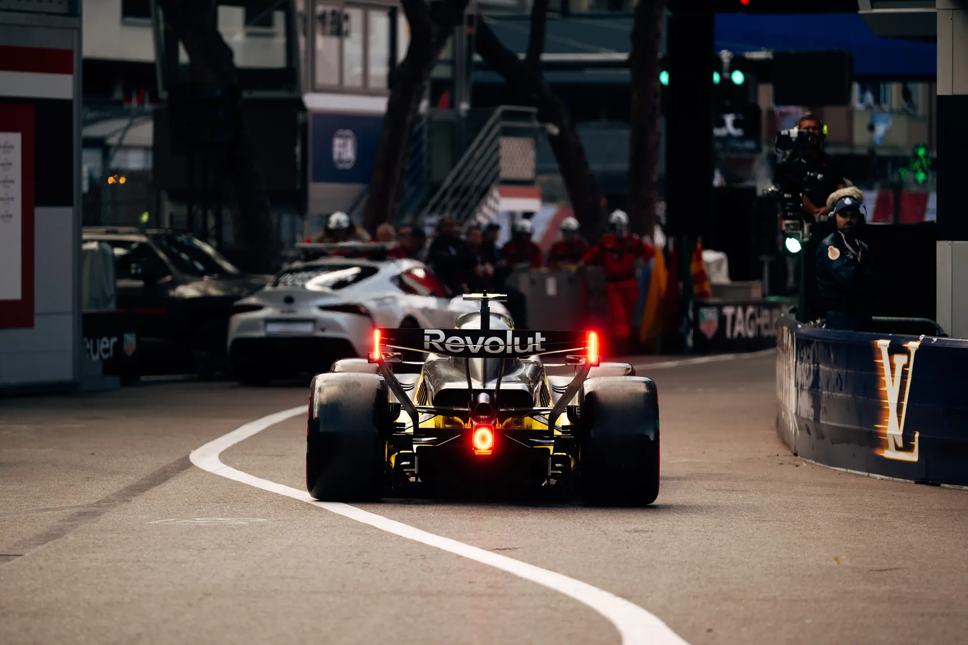 Audi Revolut F1® Team car R26 driving down the Monaco pit lane with marshals and team garages alongside.