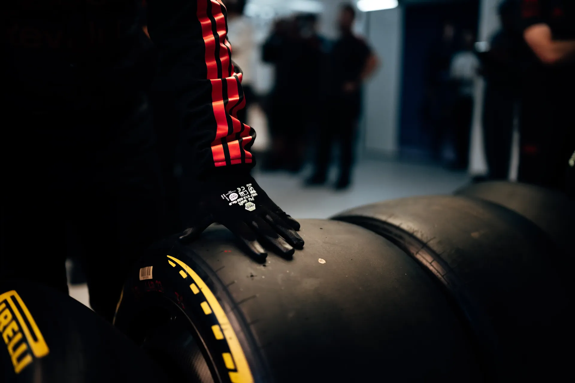 Mechanic's gloved hand resting on a Pirelli Formula 1 tyre inside the Audi Revolut F1® Team garage.