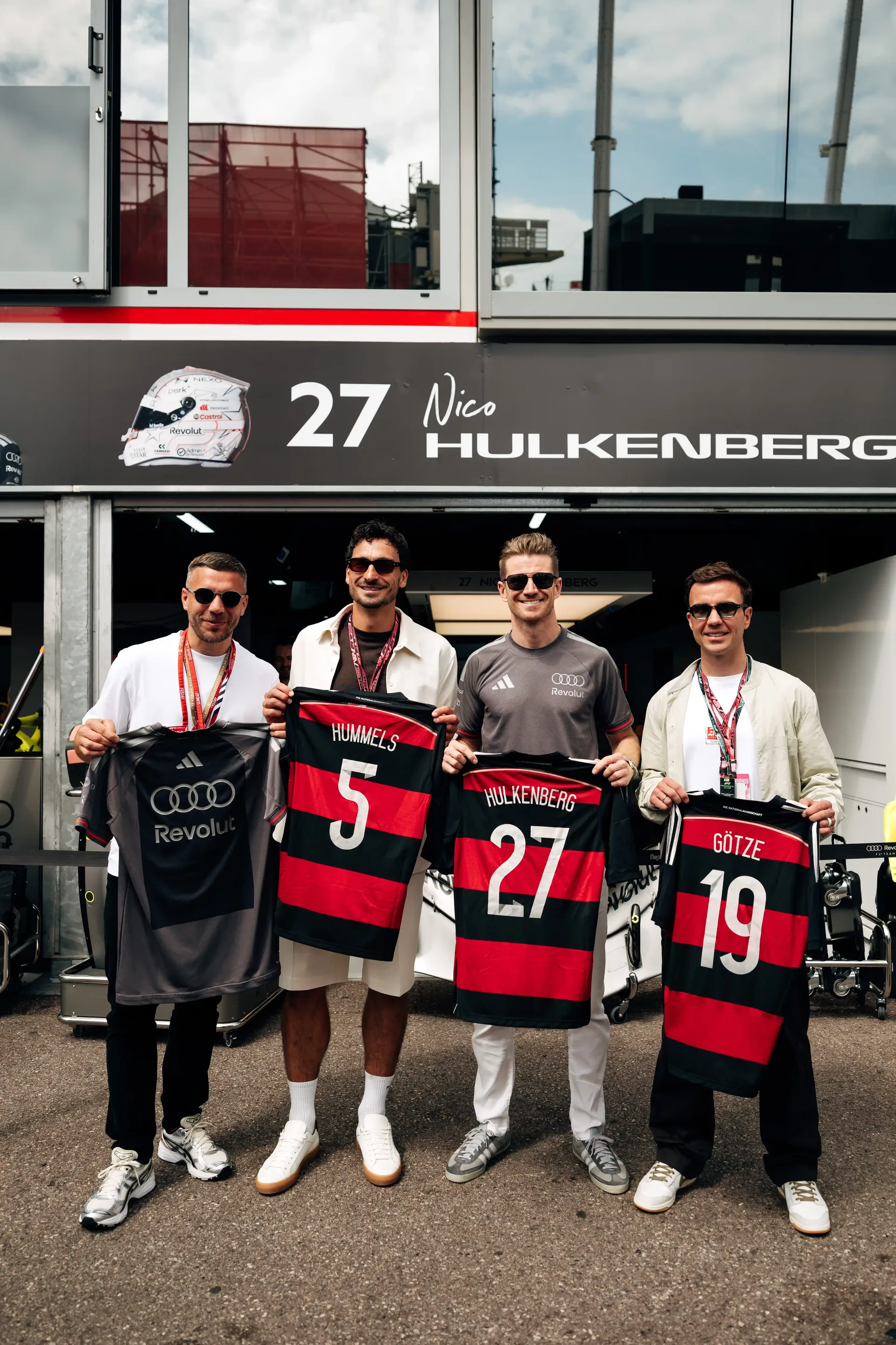 Nico Hülkenberg poses with guests holding exchanged football jerseys outside the Audi Revolut F1® Team garage in Monaco.