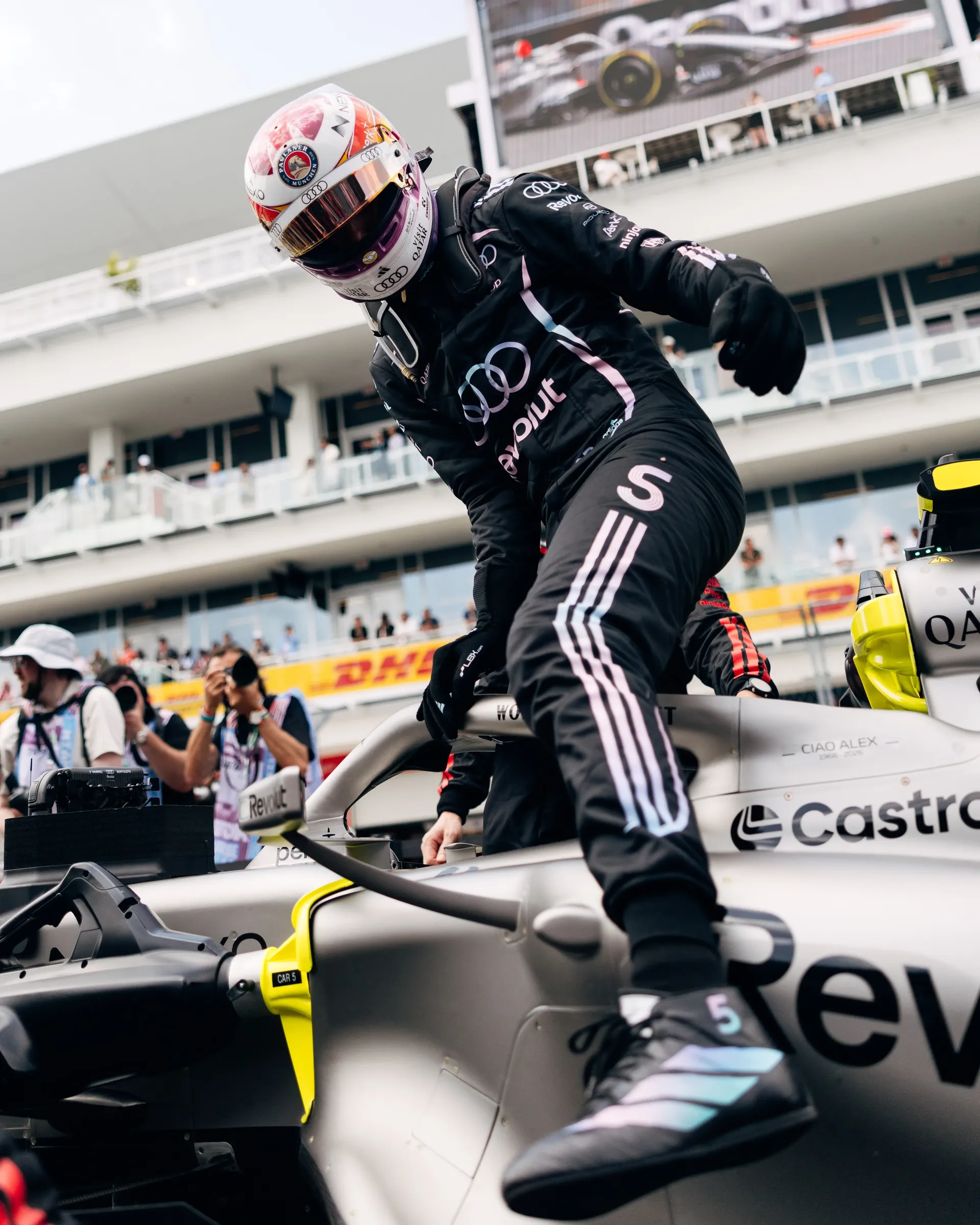 Gabriel Bortoleto climbs into his Audi Revolut F1® Team car on the starting grid in full race gear and helmet.