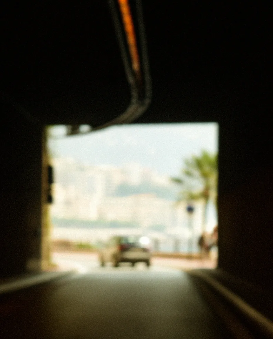 View through an arched underpass toward a sunlit Monaco street.